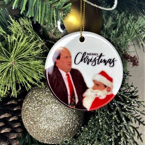 Pode incluir: Enfeite de Natal de cer&acirc;mica branca com uma foto de um homem de terno e gravata ao lado de um homem vestido de Papai Noel. O enfeite tem o texto "Merry Christmas" escrito em it&aacute;lico preto.