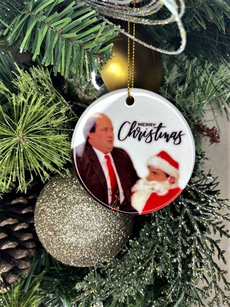 Pode incluir: Enfeite de Natal de cer&acirc;mica branca com uma foto de um homem de terno e gravata ao lado de um homem vestido de Papai Noel. O enfeite tem o texto "Merry Christmas" escrito em it&aacute;lico preto.