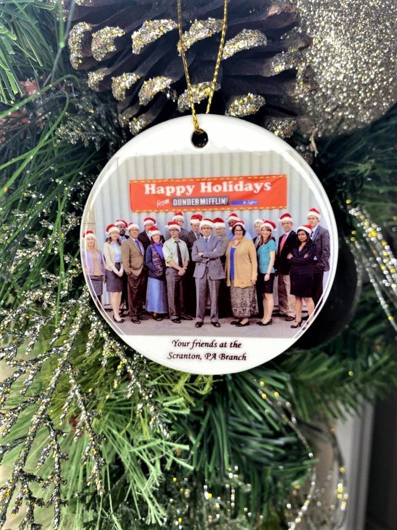 Pode incluir: Enfeite de Natal de cer&acirc;mica branca com uma foto do elenco do programa de televis&atilde;o "The Office" com o texto "Happy Holidays from Dunder Mifflin" e "Your friends at the Scranton, PA Branch".