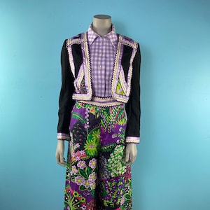 Puede incluir: Un traje de pantalón negro y blanco con una camisa a cuadros blancos y morados. La chaqueta tiene un ribete de terciopelo negro y los pantalones tienen una pierna ancha.