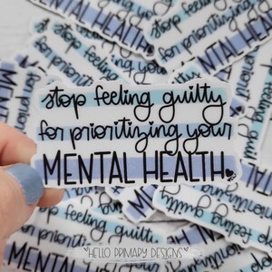 May include: A white sticker with blue stripes reads "Stop feeling guilty for prioritizing your mental health." The sticker is surrounded by other stickers with the same message.