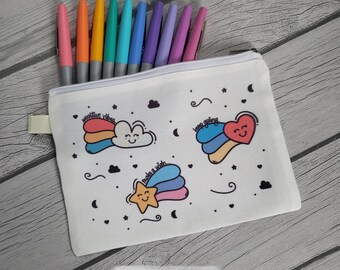 May include: A white canvas pencil case with a zipper, featuring colorful illustrations of a cloud, a shooting star, and a heart with the phrases "positive vibes", "make a wish", and "keep going". The case is filled with colorful pens.