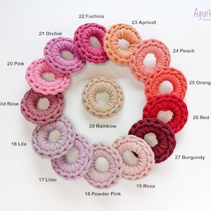 May include: Agrafka handmade crochet rings in a variety of colors, including pink, red, orange, yellow, and purple. The rings are arranged in a circle, with the colors transitioning from light to dark.