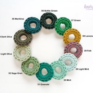 May include: A color chart of 12 crocheted rings in shades of green, yellow, and blue. The rings are arranged in a circle and labeled with their corresponding color names.