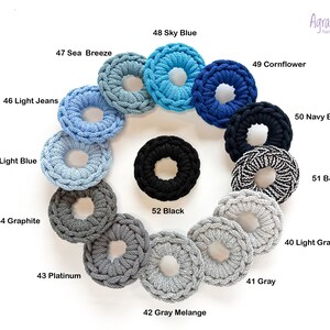 May include: A variety of crocheted hair scrunchies in different colors, including light blue, sky blue, cornflower blue, navy blue, black, gray, and white. The scrunchies are arranged in a circle on a white background.