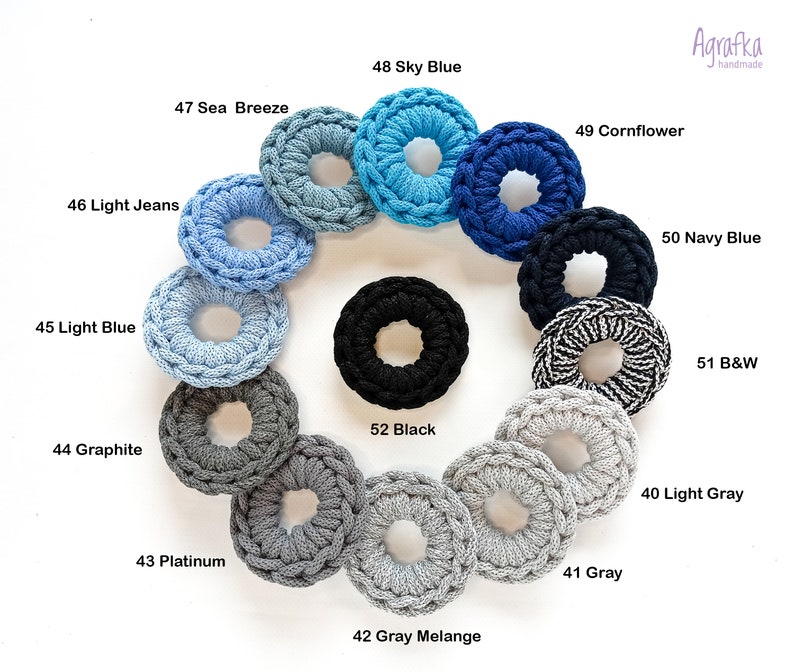 May include: A variety of crocheted hair scrunchies in different colors, including light blue, sky blue, cornflower blue, navy blue, black, gray, and white. The scrunchies are arranged in a circle on a white background.