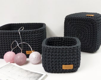 May include: Three black crocheted storage baskets of different sizes. The largest basket is a cube shape. The two smaller baskets are rectangular. The baskets have brown leather labels with the word "Agatka" on them.
