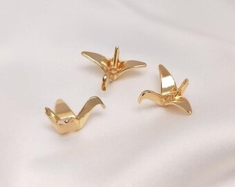 May include: Three gold origami crane charms with a hole in the center for attaching to a necklace or bracelet.