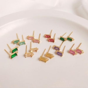May include: Assortment of colourful rectangular gemstone earring findings with gold-toned posts and loops. The gemstones are in shades of green, pink, purple, and yellow.