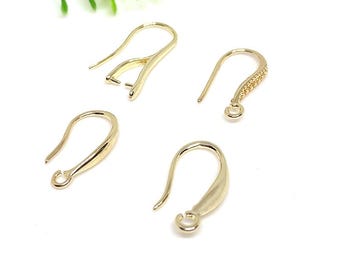 Pode incluir: Quatro ganchos de brincos dourados em vários designs. Um gancho tem um pequeno fecho, outro tem uma seção decorativa com contas, e os outros dois são ganchos curvos simples. Os ganchos estão em um fundo branco com uma planta verde no canto.