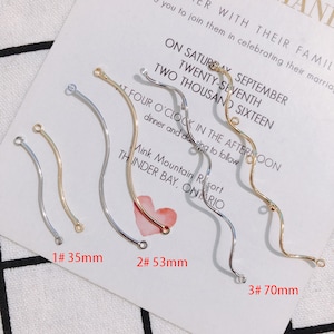 May include: Three different sizes of gold and silver wire jewelry findings. The findings are curved and have a loop at each end. The sizes are 35mm, 53mm, and 70mm.