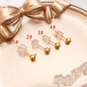 Peut inclure: Quatre tiges d'oreille en or avec des dos en plastique transparent. Les tiges sont numérotées de 1 à 4.