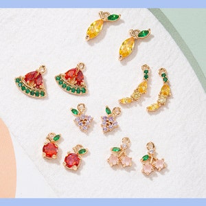 May include: Assortment of colorful fruit charm pendants with gold accents. The charms include a watermelon, lemon, cherry, and a grape. These charms are perfect for jewelry making or adding a touch of whimsy to crafts.