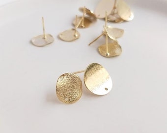 May include: Gold-toned metal earring blanks with a textured finish. The blanks are oval shaped with a small hole at the top for attaching earring posts.