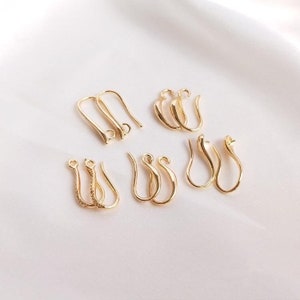 Puede incluir: Un conjunto de ocho ganchos para pendientes de oro, algunos con un diseño decorativo. Los ganchos son para la elaboración de joyas.