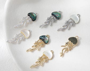 May include: A collection of jellyfish charms in silver and gold tones. The charms feature iridescent, white, and gold-colored tops with delicate, flowing tentacles. Some charms are adorned with small, sparkling accents.