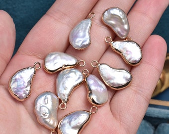 May include: Ten white baroque pearl pendants with gold-tone jump rings. The pearls are irregular in shape and have a slightly iridescent sheen.
