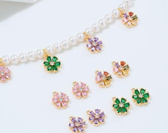 May include: A collection of floral charms and a pearl necklace. The charms are in various colors, including pink, green, purple, and yellow, with gold-colored settings. The necklace has several flower charms hanging from it.