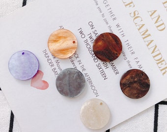 May include: Six round, flat, decorative pieces of resin with a glittery finish. The pieces are in various colors, including purple, brown, gray, beige, and white.