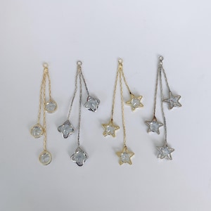 Puede incluir: Cuatro cadenas de plata y oro con abalorios de estrella y redondos de cristal. Las cadenas cuelgan de un fondo blanco.