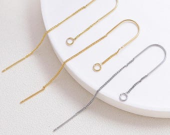 May include: Three pairs of gold and silver chain earrings with a small hoop at the end of each chain. The earrings are designed to be worn as a single earring.