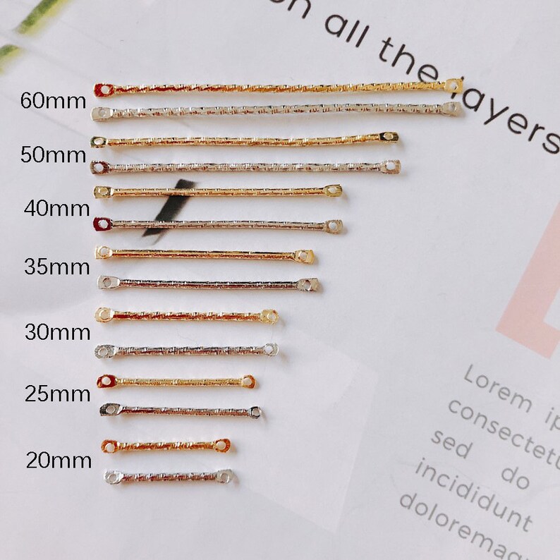 May include: A set of 10 gold and silver chain connectors in various lengths, ranging from 20mm to 60mm. The connectors are made of metal and have a textured finish. The connectors are arranged in a row from shortest to longest, with the length of each connector labeled in millimeters.