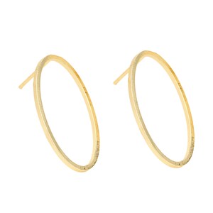 Puede incluir: Un par de pendientes de aro ovalados de oro. Los pendientes son simples y elegantes, y serían una gran adición a cualquier colección de joyas.