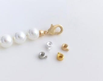 May include: A strand of white pearls with a gold clasp and three different types of metal clasps: gold, silver, and a combination of gold and silver.