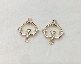May include: Two gold-tone heart-shaped pendant charms with clear crystal accents. Each charm features a smaller heart in the center and a loop at the bottom for attaching to jewelry.