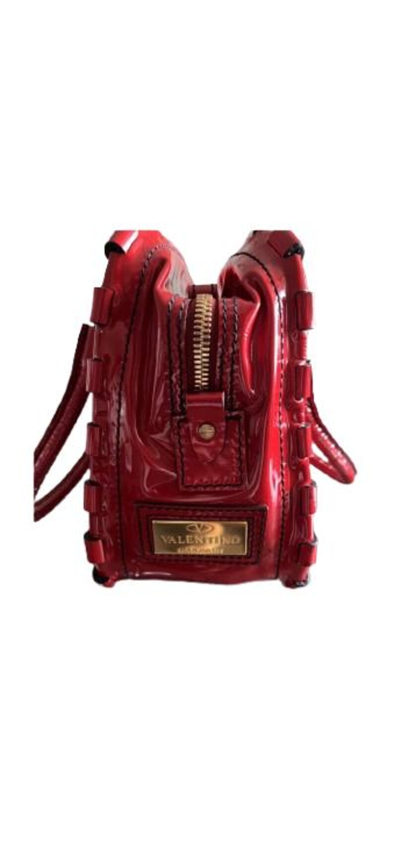 May include: A glossy red handbag with a gold zipper and handles. The bag features a rectangular gold plaque with the brand name "VALENTINO GARAVANI". The bag has a structured design with decorative stitching.