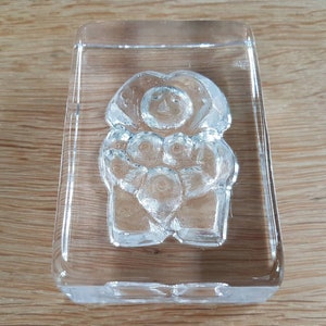 Peut inclure: Un presse-papier en verre transparent avec un motif en relief d'une personne tenant un cœur. Le presse-papier est rectangulaire et a une surface lisse et polie.