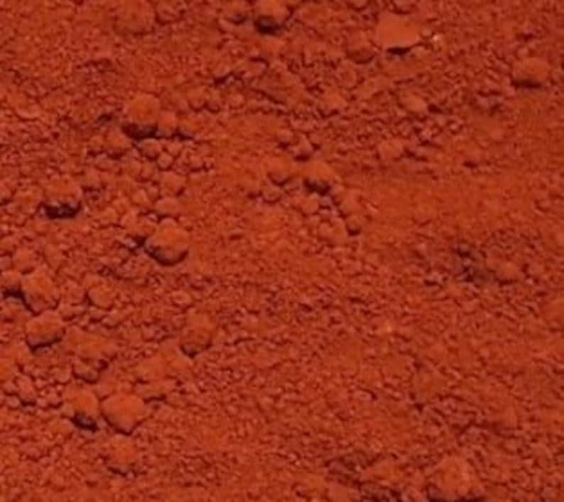 May include: Close-up of a red-brown powder, likely paprika or chili powder, with a slightly grainy texture.