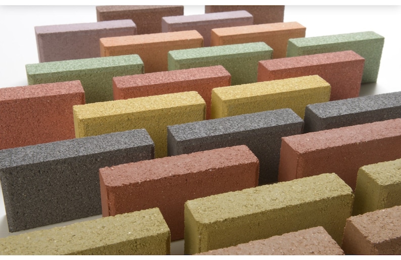 May include: A collection of rectangular concrete pavers in various colors, including red, orange, yellow, green, gray, and brown. The pavers are arranged in a staggered pattern, creating a visually appealing display.
