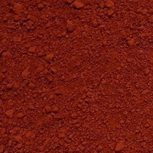 May include: Close-up of a red, finely ground powder. The powder has a slightly rough texture and is evenly distributed.