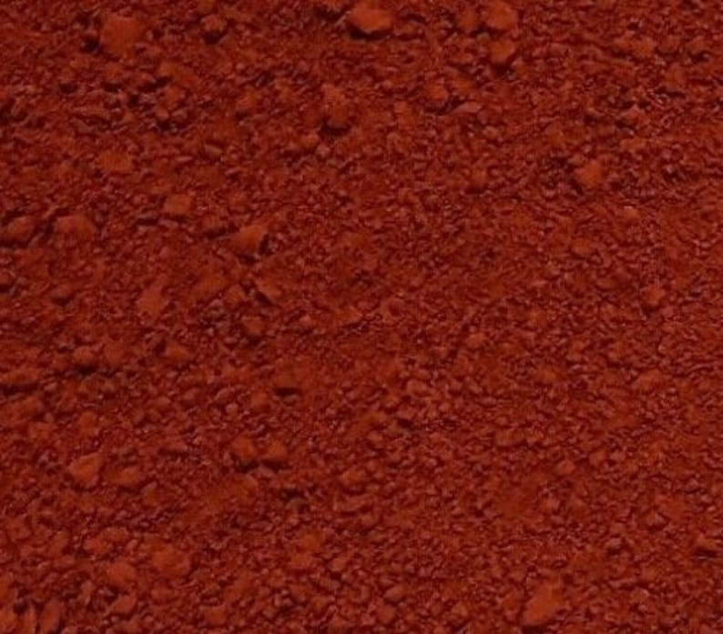 May include: Close-up of a red, finely ground powder. The powder has a slightly rough texture and is evenly distributed.