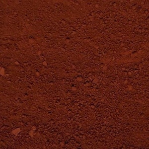 May include: A close-up of a reddish-brown powder. The powder is fine and has a slightly grainy texture.