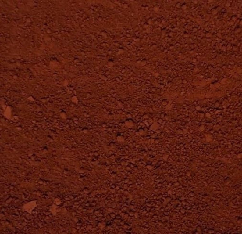 May include: A close-up of a reddish-brown powder. The powder is fine and has a slightly grainy texture.