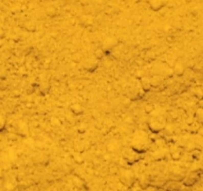 May include: A close-up of a pile of bright yellow turmeric powder.