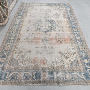 May include: A vintage rug with a cream background and a blue and brown floral pattern. The rug has a distressed look and is perfect for adding a touch of bohemian style to your home.