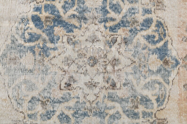 May include: A vintage rug with a faded blue and cream floral pattern. The rug has a distressed look and is made of a woven material.