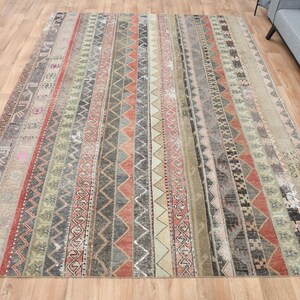 Może przedstawiać: Wietrzny dywan z paskami w odcieniach beżu, szarości i czerwieni. Dywan ma postarzony wygląd z wyblakłymi kolorami i zużytą fakturą.