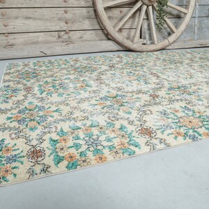 May include: A vintage floral patterned rug with a cream background and blue, green, and orange floral designs.