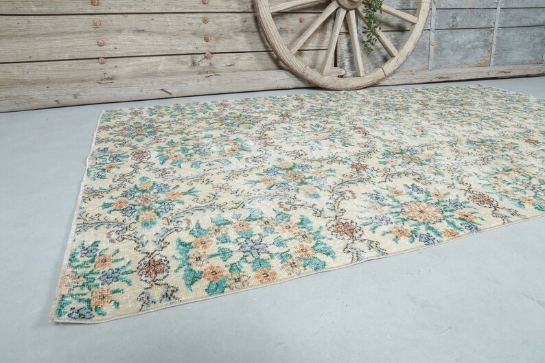 May include: A vintage floral patterned rug with a cream background and blue, green, and orange floral designs.