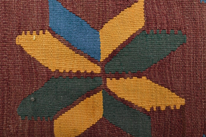 May include: Close-up of a woven fabric with a geometric pattern in shades of brown, yellow, green, and blue.