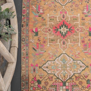 Puede incluir: Una alfombra vintage con un dise&ntilde;o persa tradicional. La alfombra tiene un fondo beige con intrincados patrones en tonos de rosa, verde y negro.