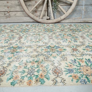 May include: A vintage floral patterned rug with a cream background and a mix of green, blue, and orange floral designs.