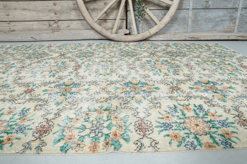 May include: A vintage floral patterned rug with a cream background and a mix of green, blue, and orange floral designs.