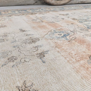 May include: A vintage rug with a faded floral pattern in shades of blue, brown, and pink on a white background.