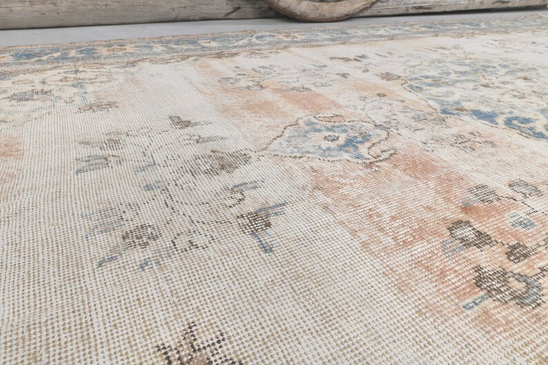 May include: A vintage rug with a faded floral pattern in shades of blue, brown, and pink on a white background.