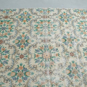 May include: A vintage rug with a cream background and a floral pattern in shades of green, blue, and orange.